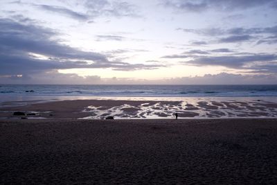 Scenic view of beach against cloudy sky