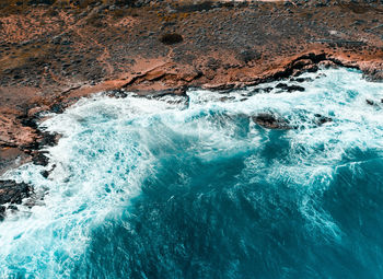 Aerial view of wave splashing on rocky coastline