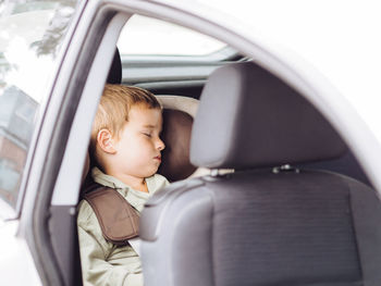 Pretty caucasian boy sleeping in safety car seat