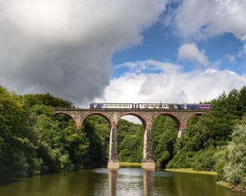 Arch bridge over river against sky