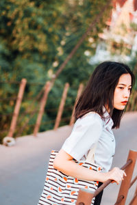 Young woman standing against tree