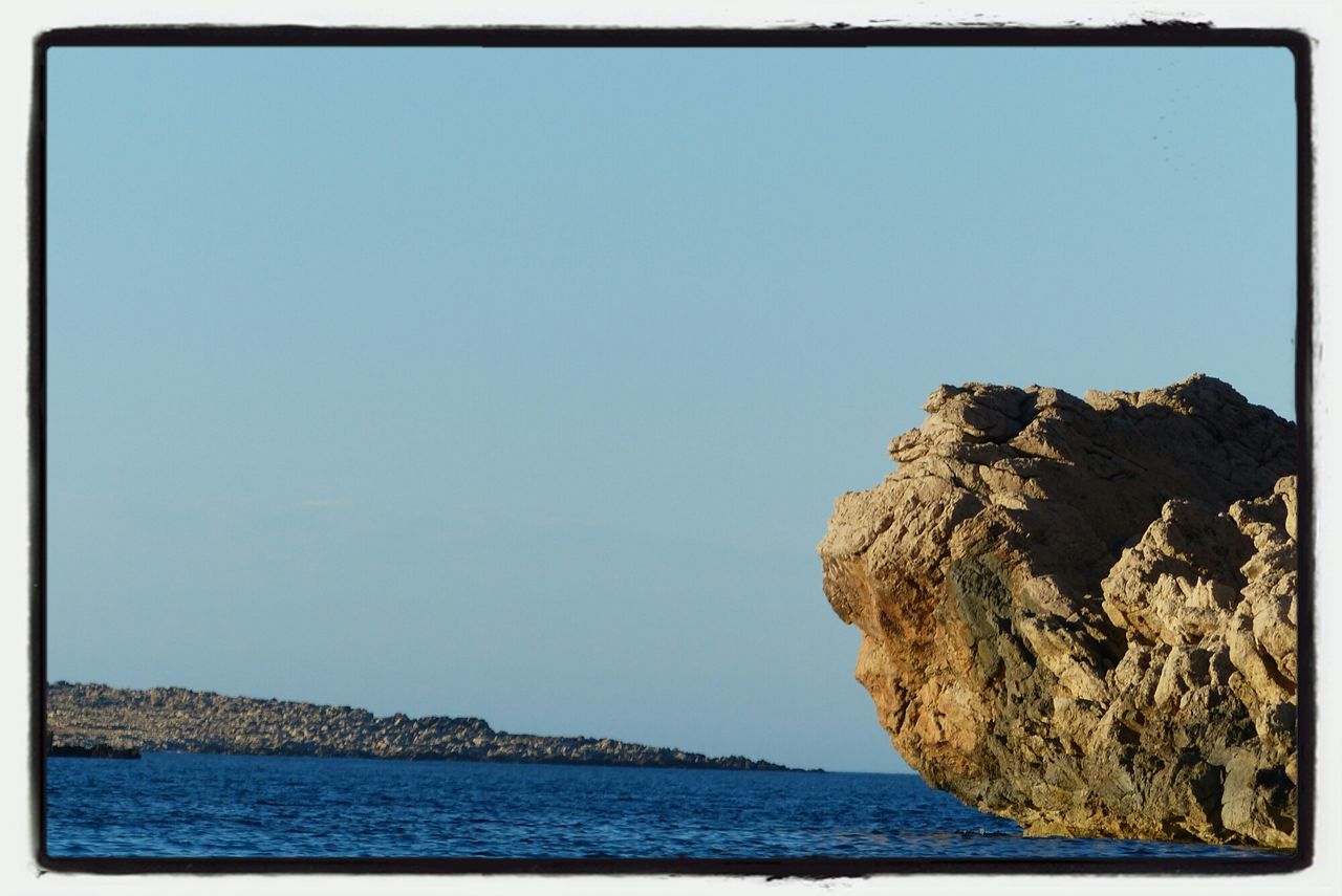 transfer print, clear sky, sea, water, copy space, tranquil scene, blue, tranquility, scenics, auto post production filter, beauty in nature, nature, rock formation, waterfront, rock - object, horizon over water, rock, idyllic, day, cliff