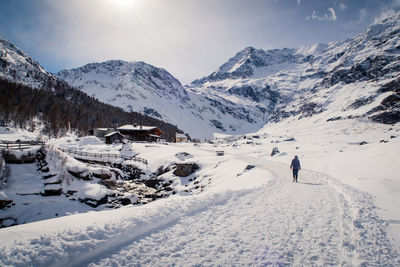 Woman walking on snowcapped mountain against sky