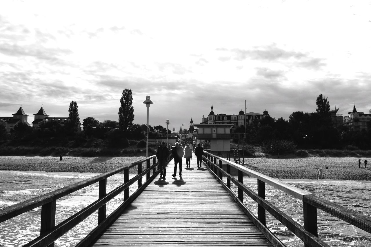 the way forward, sky, railing, built structure, walking, architecture, men, person, diminishing perspective, boardwalk, lifestyles, leisure activity, pier, rear view, building exterior, walkway, vanishing point, connection