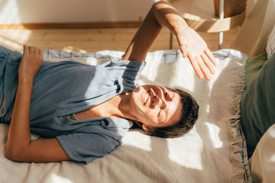 Sunbeams in the room, a woman lies on a bed in the sunbeams.