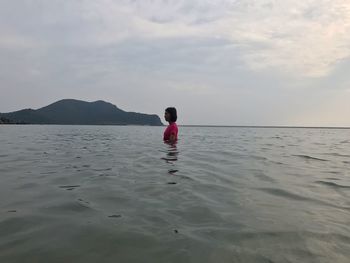 Rear view of woman in sea against sky