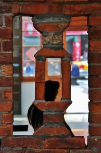 Close-up of silhouette of asian woman seen through window opening in brick wall