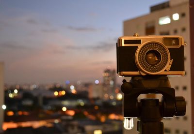 Close-up of camera against sky at sunset