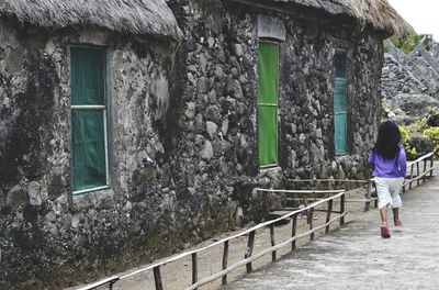 Rear view of girl running by stone houses