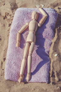 High angle view of wooden figurine on beach towel