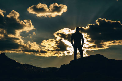 Silhouette man standing on mountain against sky during sunset