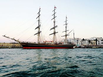 Sailboats moored on harbor against clear sky