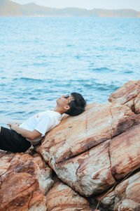 Woman relaxing on rock by sea