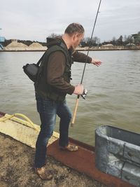 Man fishing on river against sky