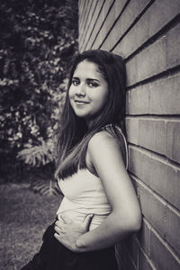 Portrait of beautiful woman sitting against wall