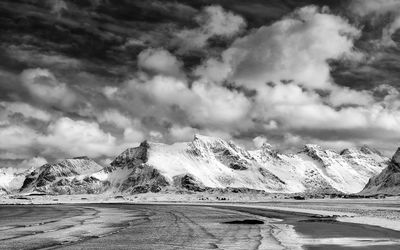 Scenic view of snowcapped mountains at beach against cloudy sky