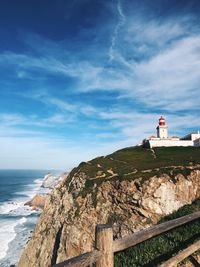 Lighthouse by sea against sky