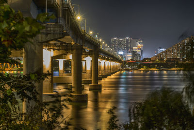 Illuminated bridge over river at night