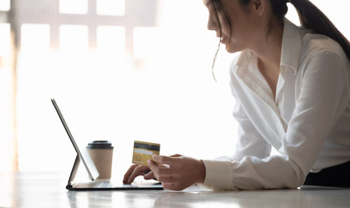 Woman using mobile phone while sitting on table