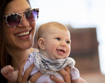 Woman carrying daughter against sky