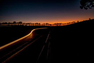 Light trails on road against sky during sunset