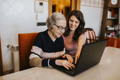 Granddaughter teaching her grandmother something on the laptop