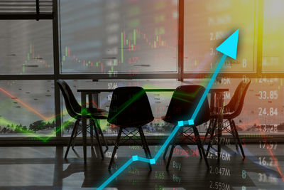 Empty chairs and table by glass window