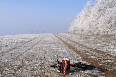 Bicycle on field against sky during winter
