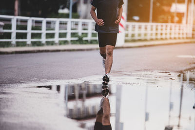 Low section of man running on wet glass