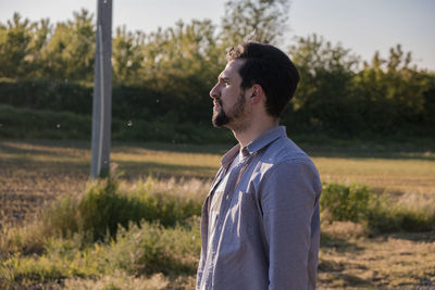 Side view of young man looking away on field