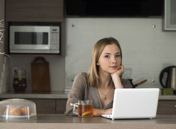 Portrait of woman using laptop at home