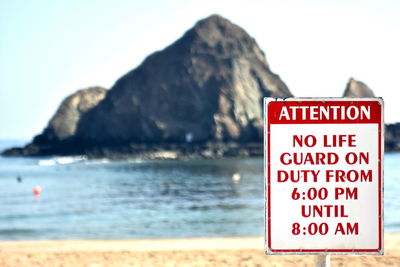 Information sign on rock by sea against sky