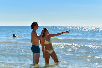 Couple standing on beach against sky