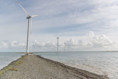 Wind turbines on sea shore against sky