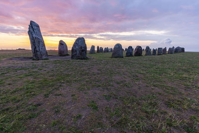Panoramic shot of rocks on field against sky during sunset
