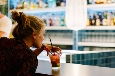 Midsection of woman drinking glass on table at restaurant