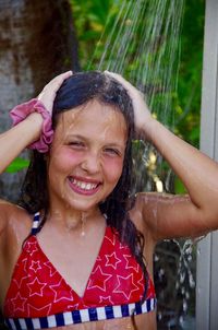 Close-up portrait of smiling girl showering outdoors