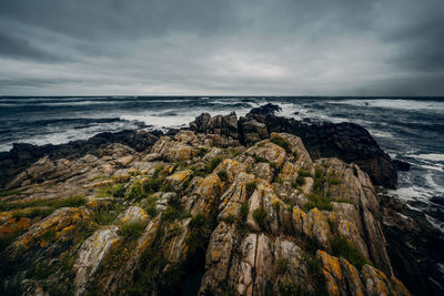 A seascape with stormy clouds and rocks leading out to the waves