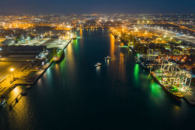 High angle view of illuminated city by river at night