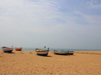 Boats moored on beach against sky