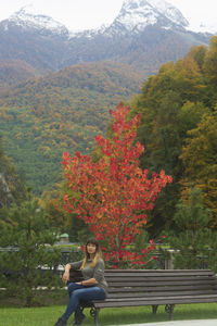 Woman sitting on tree by mountain