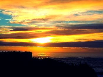 Scenic view of sea against dramatic sky during sunset