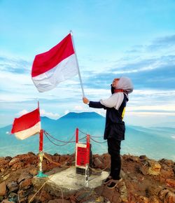 Woman standing by flag against sky