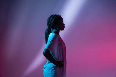 Side view of woman standing against pink wall