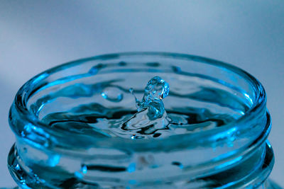 Water drop and splash falling into a glass of water with an aqua blue tinge