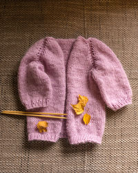 Knitted jacket for a girl, pink color, knitting texture, handicraft concept, hand knitting