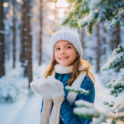 The joy of the winter. portrait of smiling young girl in a snowcapped forest, wearing warm clothes.