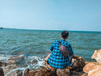 Rear view of man on beach against sky