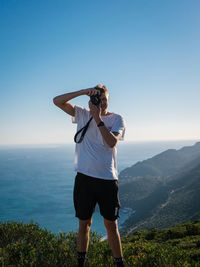 Rear view of woman standing against sea against clear sky