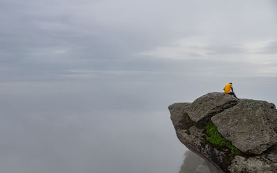 Man on rock against sky